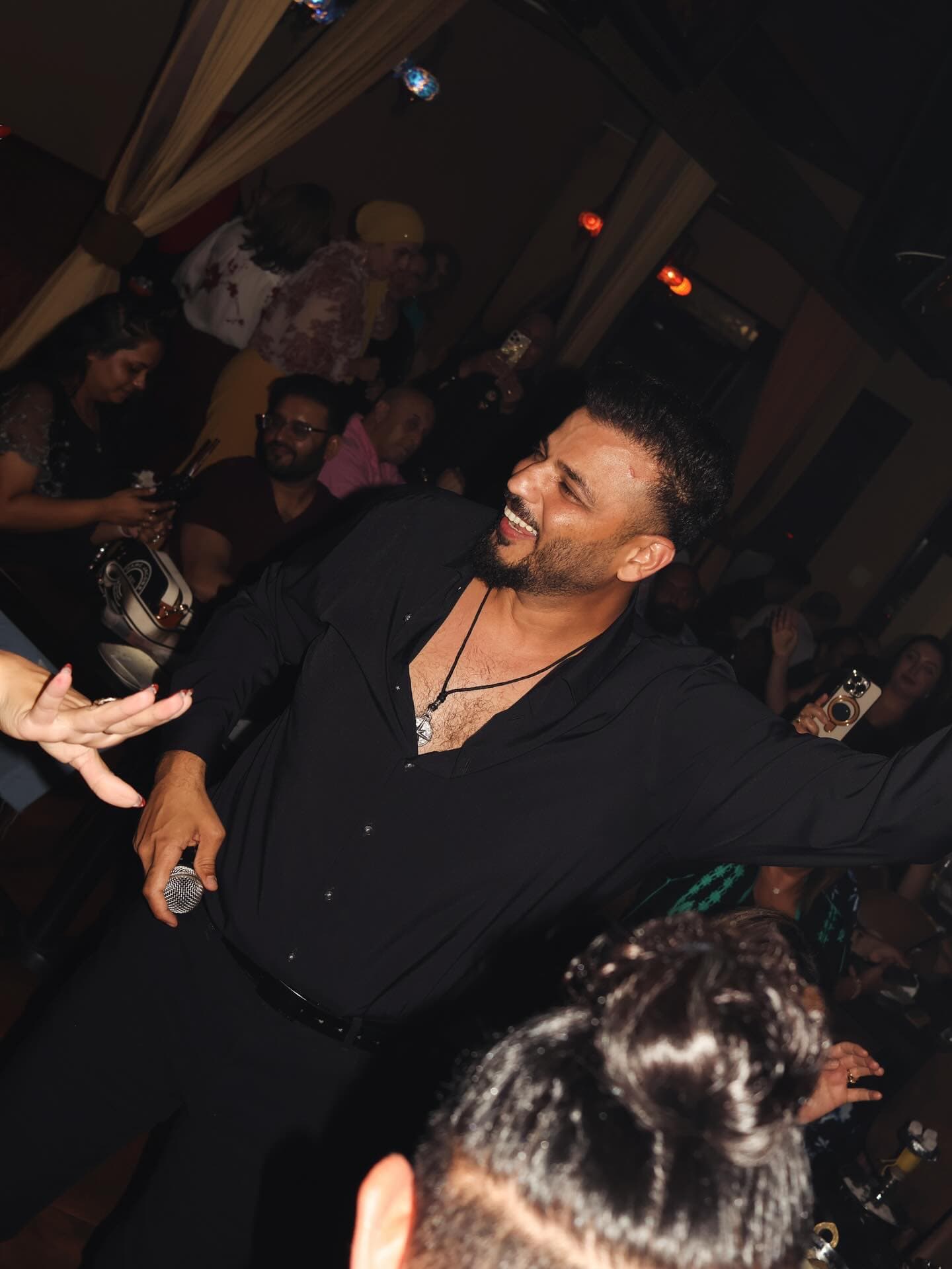 The singer in the middle of the room, arms wide, tables full